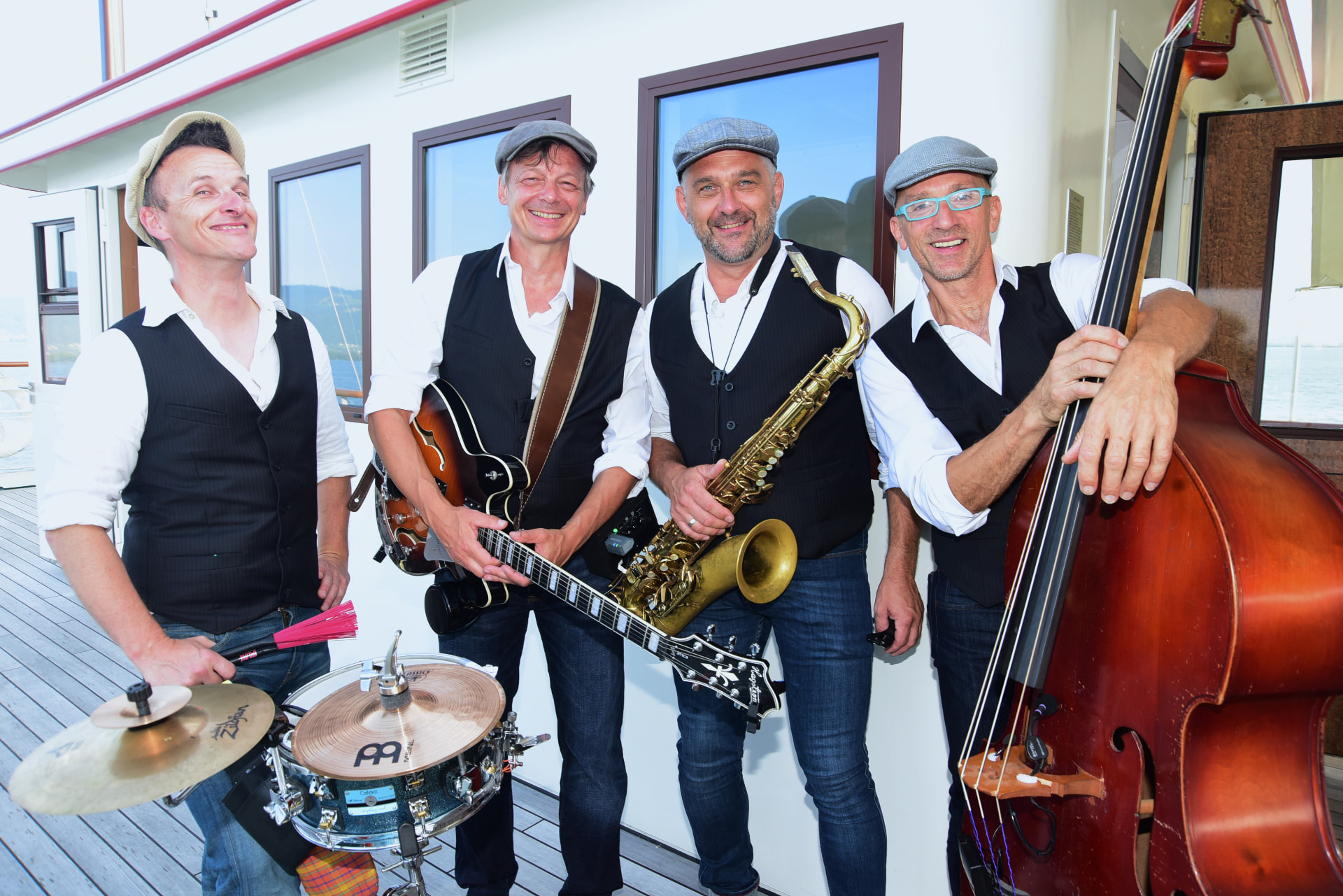 Die vier Swingbugs posieren mit ihren Instrumenten für ein Gruppenfoto an Deck